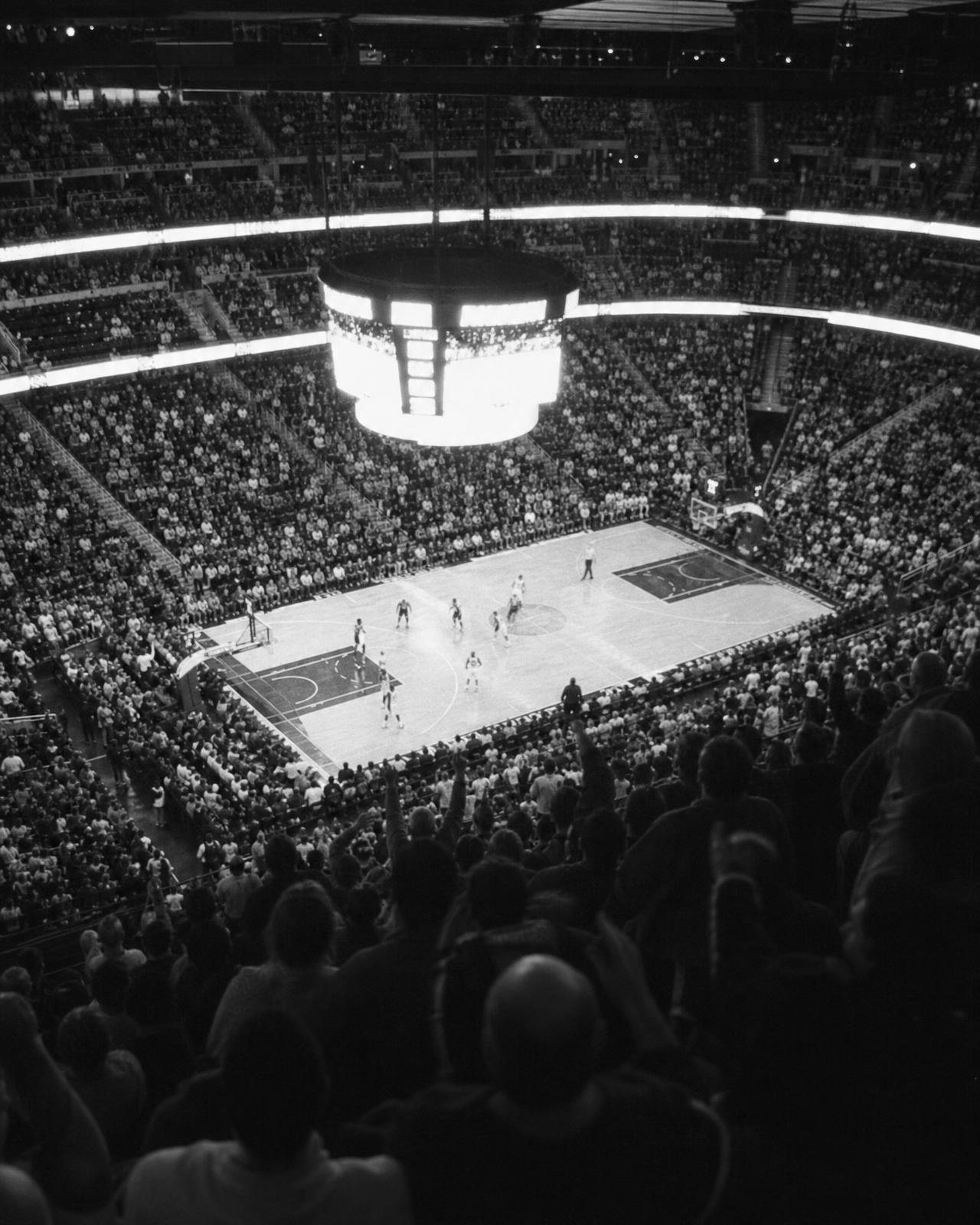 Packed arena bowl during a game, display boards glowing above the court